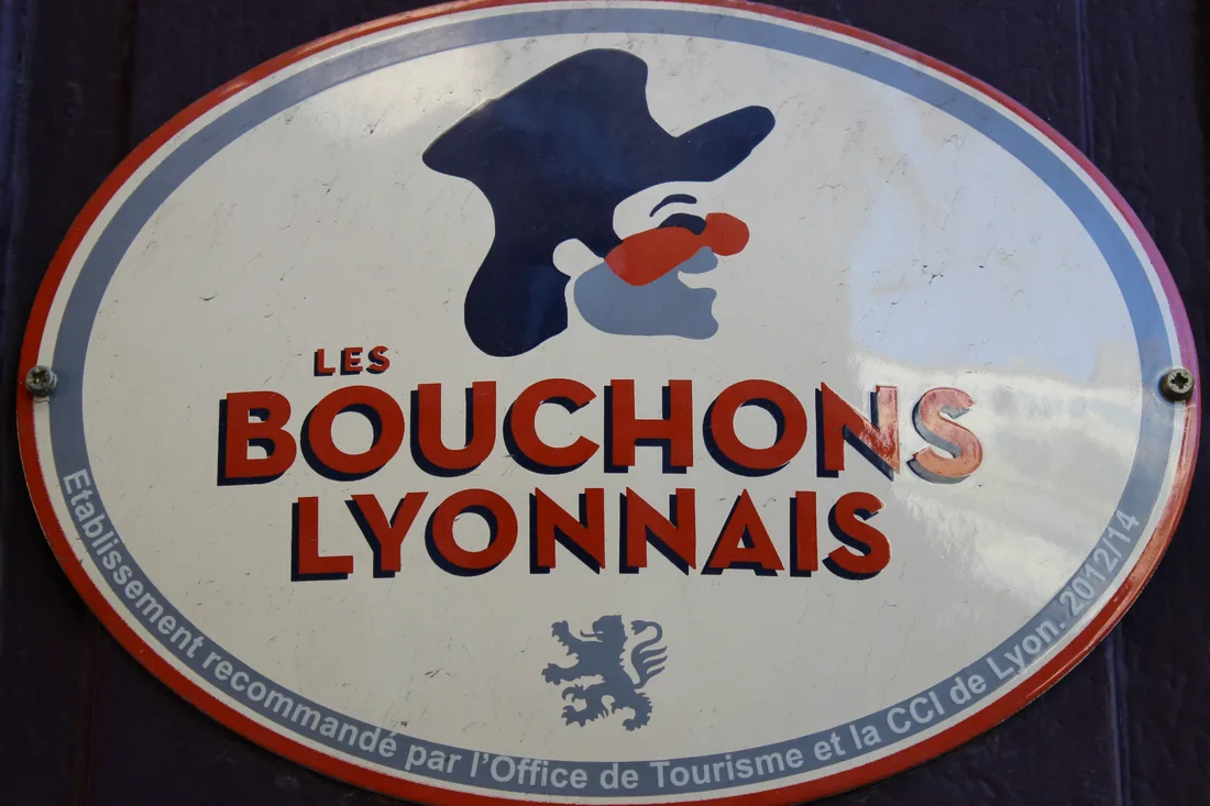 Эмалевая табличка ассоциации Les Bouchons Lyonnais с профилем Гнафрона на фасаде бушона
